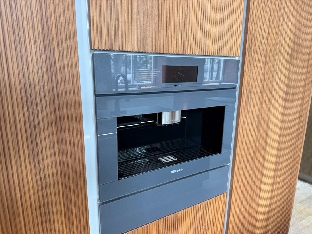 Built-in Miele bean to cup coffee machine set flush into a run of ribbed timber tall units, Arlington Interiors showroom, Farsley.