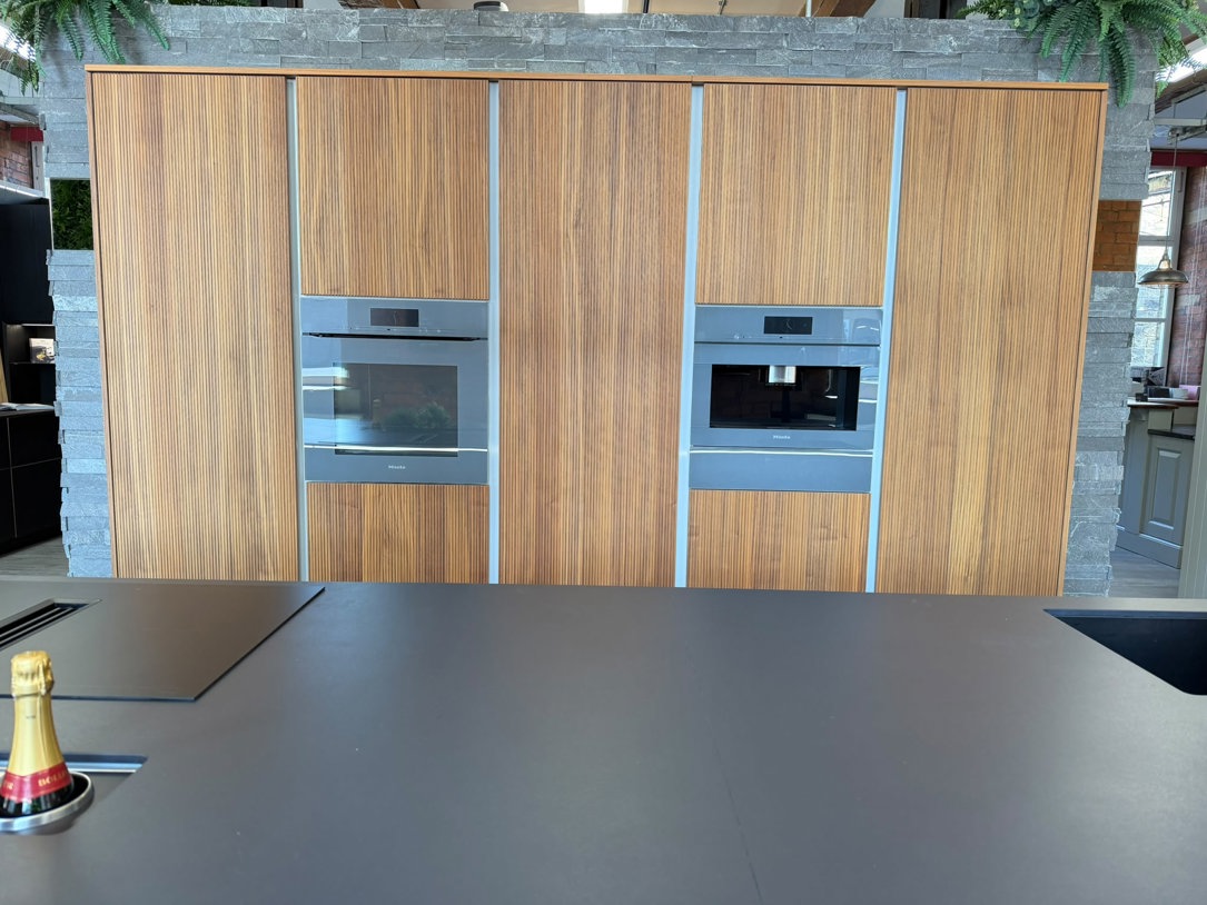 Miele integrated larder fridge concealed behind a ribbed timber furniture door in a run of tall units, Arlington Interiors showroom, Farsley.